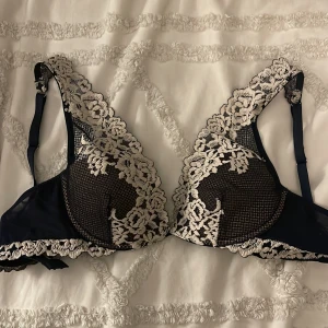 Mörkblå spets-bh med blommigt mönster från intimissini - Snygg mörkblå bh med vacker vit spets och blommigt mönster. Den har justerbara axelband och en elegant design som passar perfekt för speciella tillfällen. Perfekt för att känna sig extra fin och bekväm. Ingen push up aldrig använd.