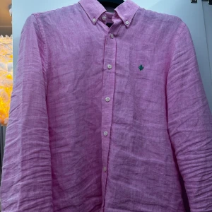 Rosa linneskjorta från Morris - Säljer en snygg rosa skjorta från Morris i 100% linne. Perfekt för vår och sommar med sin lätta och luftiga känsla. Skjortan har långa ärmar och knappar framtill. Den är i mycket bra skick och passar både till vardags och fest. 🌸