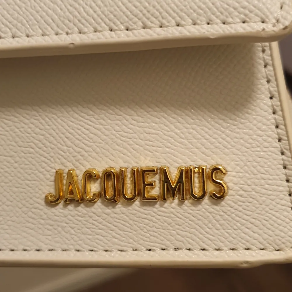 Säljer en superfin vit handväska från Jacquemus i skinn. Den har en stilren design med ett litet handtag och en axelrem. Perfekt för att lyfta vilken outfit som helst! Väskan är i nytt skick och har en snygg gulddetalj med märkesnamnet på framsidan.. Laukut & Käsilaukut.