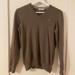 Beige tröja från J.Lindeberg - Säljer en snygg brun tröja från J.Lindeberg i mycket fint skick. Nypris ca 1100kr, mitt pris 399kr. Den har en stilren v-ringning och långa ärmar, perfekt för både höst och vår. Tröjan är i en normal passform och känns riktigt skön att ha på sig. Passar både till vardags och lite finare tillfällen.