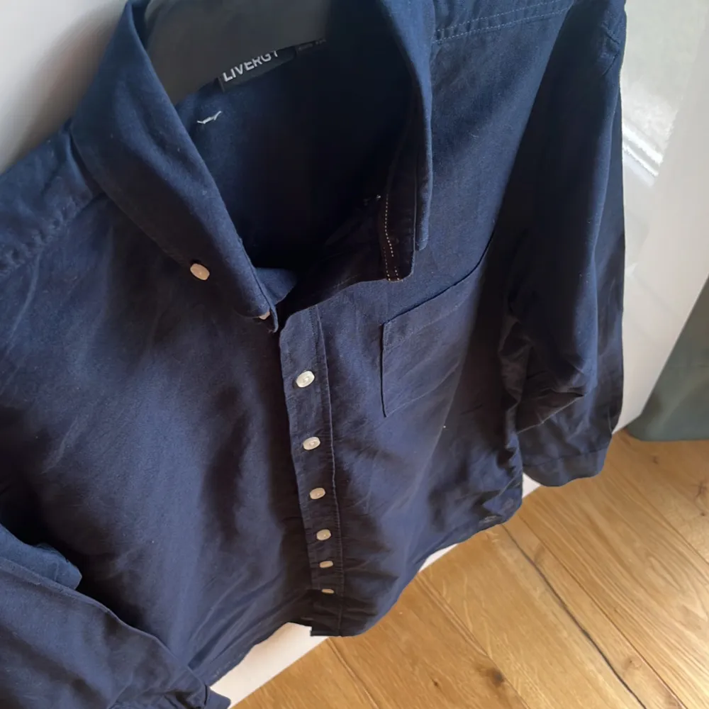 Säljer en stilren mörkblå skjorta från Livergy i storlek M. Skjortan har långa ärmar och knappar framtill samt en bröstficka. Perfekt för både vardag och festliga tillfällen. Materialet känns bekvämt och passar bra till höst 🍂 mm. Mvh ItsForFits 🌟. Paidat.