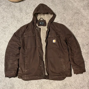 Carhartt jacka - Fodrad Carhartt jacka. Har använts två vintrar. Är lite små sliten och kan ha något enstak hål. Köpte för 1800. Skriv om frågor finns
