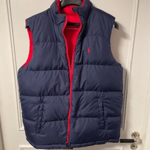 Ralph lauren väst (vändbar) - En super fin Ralph lauren väst i bra skick ingen slitning eller hål någonstans den är vändbar så man kan välja om man vill ha en röd eller mörkblå 
