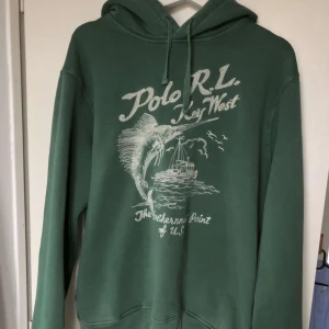Grön hoodie från Polo RL - Säljer en snygg grön hoodie från Polo RL med tryck. Perfekt för en avslappnad stil. Den har en klassisk passform med långa ärmar och en skön huva med dragsko. Perfekt för höst och vår! Storlek M men passar även S