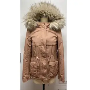 Säljer en snygg rosa-beige parkajacka med fuskpäls på huvan. Jackan har långa ärmar och praktiska fickor framtill. Perfekt för höst och vinter, med dragkedja och knappar för extra värme. Den har en justerbar midja för bättre passform. Supermysig och stilren!