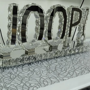 Dekorativ skylt med texten JOOP! - En glittrig och elegant dekorativ skylt med texten JOOP! i stora bokstäver. Skylten är täckt med kristallliknande detaljer som reflekterar ljus och ger en lyxig känsla. Perfekt som inredningsdetalj för att ge rummet en touch av glamour.