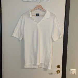 Vit pikétröja i bomull - Säljer en klassisk vit pikétröja i bomull från Regular Fit. Perfekt för sommardagar eller en avslappnad stil. Tröjan har korta ärmar och en bekväm passform. Passar både till vardags och lite finare tillfällen. 🏖️Pris går alltid att förhandlas!
