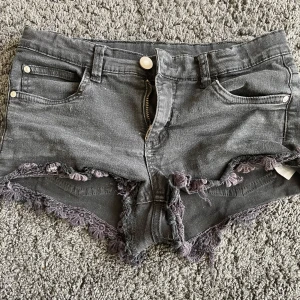 Grå jeansshorts med fransar - Säljer ett par grå jeansshorts i bra skick. De är lågmidjade med fransiga kanter och har både fram- och bakfickor. Perfekta för sommaren och festivaler!