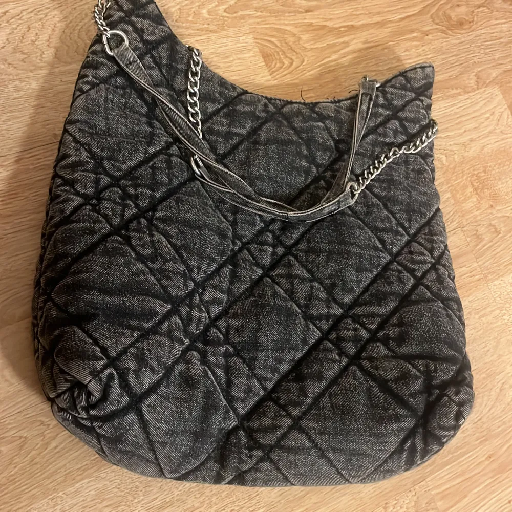 Snygg svart quiltad axelväska med kedjedetaljer och en praktisk dragkedja. Perfekt för att bära dina dagliga nödvändigheter med stil. Väskan har en rymlig insida och en säker stängning.. Laukut & Käsilaukut.