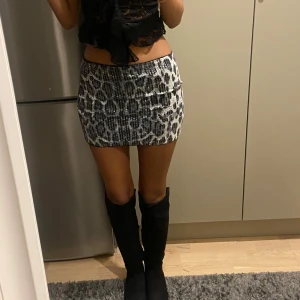 Leopardmönstrad kortkjol - Trendig leopardmönstrad kortkjol i svart och vit. Perfekt för att sticka ut med en djärv stil. Kjolen har en tight passform som framhäver figuren.