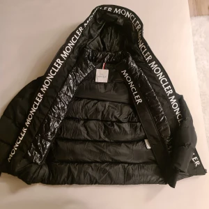 Svart dunjacka från Moncler - Säljer min fantastiska Montclair Short Down Jacket i storlek 0, som passar bra för dig som vanligtvis bär storlek S. Jag är själv XS och den sitter perfekt!   Jackan är i perfekt skick och har verkligen varit en livräddare under kalla dagar. Den höll mig supervarm även när temperaturen sjönk till -9 grader. Fylld med vit gåsdun, ger den en otrolig värme och komfort. 