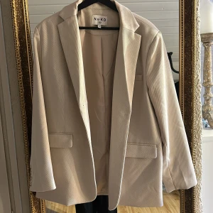 Beige kavaj från NA-KD - Snygg beige kavaj från NA-KD med klassisk design. Den har en normal passform och långa ärmar.