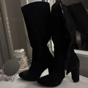 Svarta stövlar med klack - Snygga svarta stövlar med hög klack och dragkedja på sidan. Mocka material, storlek 39, aldrig använda, pris 300:- vid frågor kontakta mig 🫶🏽