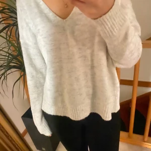 Gråvit tröja från JDY - Mysig vit  tröja från JDY med v-ringning och användning av gå. Perfekt för kyliga dagar. Tröjan har långa ärmar och ribbade kanter som ger en stilren look, dessutom är den otroligt skön!🤍🧸