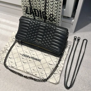 Zadig & Voltaire väska  - Säljer nu min fina Zadig & Voltaire handväska som är svart mönstrad. Lite unikare design. Kommer med allt på bilden, finns både kort och lång svart kedja. Köpt för ca 3000kr i deras butik i Sthlm! 🪽