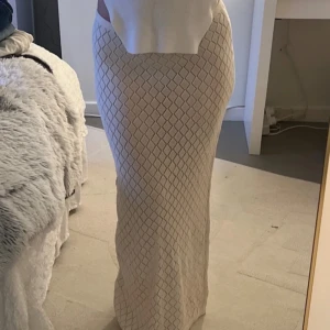 Vit långkjol med rutigt mönster - Snygg vit långkjol med ett diskret rutigt mönster. Kjolen har en tight passform som framhäver figuren. Perfekt för en stilren look.