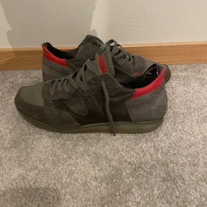 Philip model - Snygga sneakers i grått och rött från philip model Skorna har en klassisk design med snörning och är tillverkade i mocka och syntetmaterial. Perfekta för en stilren look. Lite sönder på baksidan inne i skon kom privat för fler bilder 