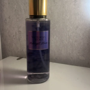 Midnight Bloom Body Mist från Victoria's Secret - Fräsch och blommig body mist från Victoria's Secret i doften Midnight Bloom. Flaskan är genomskinlig med en lila ton och har en elegant guldfärgad kork. Perfekt för en uppfriskande känsla när som helst. Använd väldigt lite, 250ml