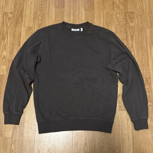 Mörkbrun sweatshirt från Weekday - Säljer en stilren svart sweatshirt från Weekday i storlek S. Tröjan har en klassisk rund halsringning och långa ärmar med ribbade muddar. Perfekt för en avslappnad look.