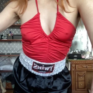 Röd halterneck topp - Snygg röd halterneck topp med justerbar urringning och rynkade detaljer framtill. Toppen har en knytning i nacken och är stretchig.  Längd: 38cm