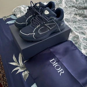 Blå sneakers från Dior - Snygga blå sneakers från Dior med vita detaljer och snörning. Skorna har en modern design med märkets logotyp på sidan och en bekväm sula.
