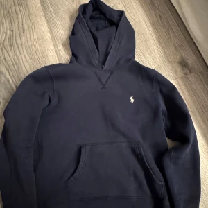 ..pris kan diskuteras.. mörkblå hoodie från Polo Ralph Lauren. Det är i barn storlek  - Säljer en stilren svart hoodie från Polo Ralph Lauren med klassisk logga på bröstet. Tröjan har en bekväm passform och en praktisk magficka. Perfekt för en avslappnad look.