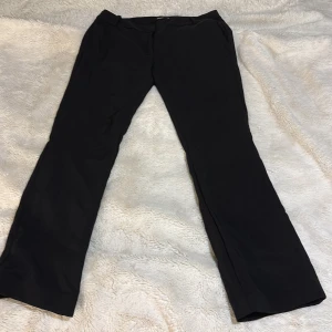 Svarta kostymbyxor - Säljer ett par kostymbyxor som tyvärr är för stora för mig. Har försökt minska dem genom att tvätta, och har dessutom använt ”sylim” för att göra dem kortare i längden, det är det ni ser på bild 4. Går enkelt att få bort limmet om man vill ha den i orginal längd. Använt 1 gång. 