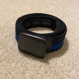 Svart och blått bälte Paul Smith - Snyggt svart bälte med en blå rand och ett robust metallspänne. Perfekt för att ge en stilren touch till din outfit.