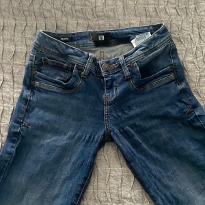 Blå jeans från LTB - Snygga blå jeans från LTB med klassisk femficksdesign och knappgylf. Perfekta för en avslappnad stil med en lätt tvättad look. Jeansen har lite utöjningar på vissa ställen men inget man tänker på när man använder de! Jeansen är i storlek 25/30 