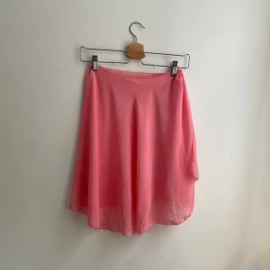 Rosa kjol - Säljer en söt rosa kjol med asymmetrisk design. Kjolen har en luftig passform och är perfekt för varmare dagar. Den är gjord i ett lätt material som ger ett fint fall.       Den är väldigt genomskinlig och har själv haft den för en dans show och hade då shorts under, passar nog till sommaren. 