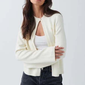 Vit kofta med knappdetalj - Snygg vit kofta med en enkel knapp framtill. Den har långa ärmar och en stilren design som passar perfekt till både jeans och kjol. Perfekt för lager-på-lager under kyligare dagar. Fick i julklapp men inte riktigt min stil, har inte använt den så den är helt ny💕 nypris 359 men säljer för 300