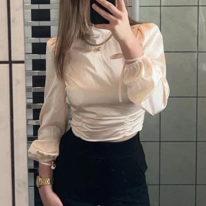 Vit blus med puffärmar - Elegant vit blus med långa puffärmar och rynkdetaljer i midjan. Perfekt för en stilren look.