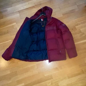 Tommy hilfiger jacka - Hej, säljer min tommy hilfiger jacka. Passformen är medium och kan passa small. Den är väldigt varm och perfekt för vinterns kalla månader. Små schyssta detaljer på små ställen vilket ger den mer karaktär samt innerficka på vänster sida. OBS har en lagning på höger arm men syns knappt. Annars är den felfri. Priset är ej hugget i sten.