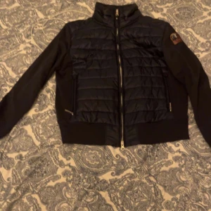 Mörkblå  jacka från Parajumpers -  Snygg mörkblå  jacka från Parajumpers med quiltad design och dragkedja framtill. Jackan har en hög krage och ett märke på ärmen. Perfekt för kyligare dagar. Nypris 3000