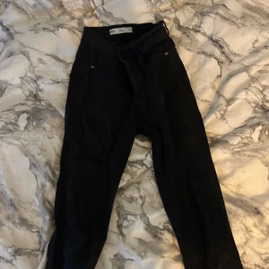 Svarta byxor med hög midja - Snygga svarta tighta byxor med hög midja och knappar. Perfekta för en stilren look. Passar bra till både vardag och fest.