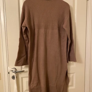 Beige stickad klänning från BikBok - Mysig beige stickad klänning från BikBok i storlek XS. Klänningen har en ribbad design och långa ärmar, perfekt för kyligare dagar. Tillverkad av en blandning av viskos, polyester och polyamid. Klänningen är enbart provad, dock är prislapp bortklipp 