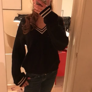 Svart stickad tröja från H&M - Säljer en svart stickad tröja från H&M med vita ränder vid v-ringningen och ärmsluten. Används inte längre! Kolla min bio för mer info💗