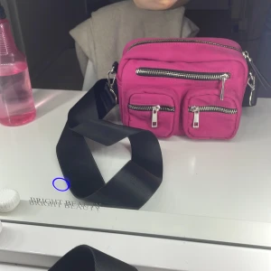 Rosa axelväska med dragkedjor - Snygg rosa axelväska från Carin wester köpte den för ungefär 1200 kr med flera praktiska dragkedjor och justerbar svart axelrem. Perfekt för att hålla ordning på dina saker med stil. Den är sönder inuti och har en fläck men den syns inte om man kollar ordentligt med ett ljus.