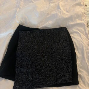 Svart kortkjol från C'est Normal - Snygg svart kortkjol från C'est Normal. Kjolen har en stilren design med en diskret glittrig yta som ger en extra touch. Perfekt för att lyfta vilken outfit som helst.fick i julklapp aldrig andvönd 