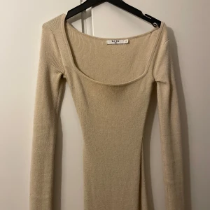 Beige ribbad långklänning från NA-KD - Snygg beige långklänning från NA-KD med ribbad design och långärmad stil. Perfekt för en stilren look med en rundad halsringning som ger en elegant touch. Insydd.