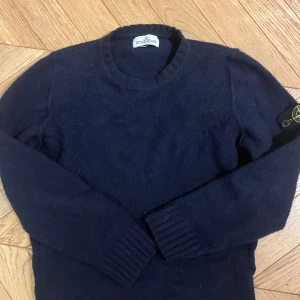 Mörkblå stickad  tröja i ull  från Stone Island Junior - Säljer en snygg mörkblå tröja från Stone Island Junior. Tröjan har långa ärmar och en rund halsringning. Perfekt för kyligare dagar med sin stilrena design och ikoniska logga på ärmen.