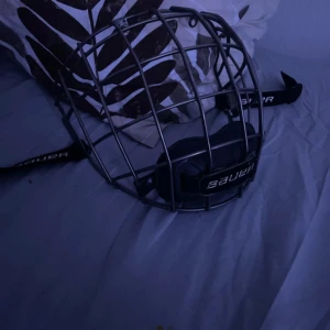 Hockeygaller från Bauer - Säljer ett robust hockeygaller från Bauer. Perfekt för att skydda ansiktet under intensiva matcher. Gallret är i metall och har en justerbar rem för säker passform.