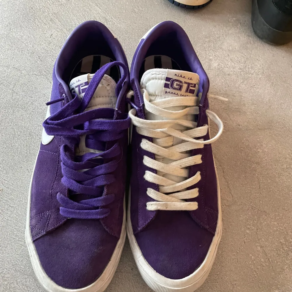 Säljer ett par lila Nike sneakers med vit sula och vit swoosh. Skorna har snörning och en stilren design, perfekt för vardagsbruk.. Kengät.