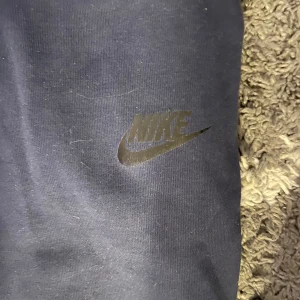 Mörkblå mjukisbyxor från Nike - Säljer ett par mörkblå nike tech byxor. Skick 10/10 typ aldrig använda. Säljer på grund av att dom aldrig används och dom är för små. Storleken är XL i barn storlek så de är samma dom 170cm. Pris kan diskuteras vid en snabb affär 