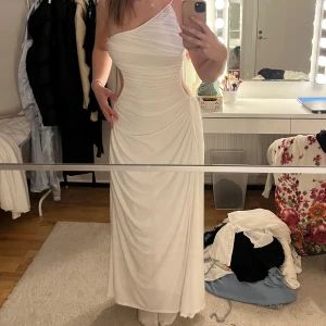 Vit sndy MONACO klänning - Elegant vit oneshoulder klänning med draperad design och öppen rygg. Perfekt för speciella tillfällen med sin långa längd och stilrena look. kan tänka mig att byta mot en likadan klänning i storlek M. exlusivt märke ❤️Heöt ny (lapp kvar)