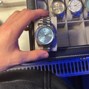 Seiko klocka - Elegant klocka med en skimrande blå urtavla och romerska siffror. Boetten och armbandet är i silverfärgat stål, vilket ger en stilren look. Perfekt för den som vill ha en tidlös accessoar. PRIS GÅR DISKUTERA TAR GÄRNA BYTEN 