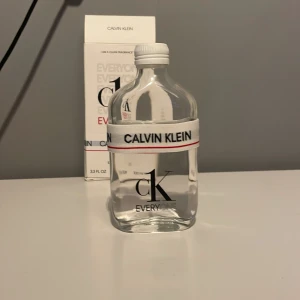 CK Everyone Eau de Toilette från Calvin Klein - Säljer en fräsch och modern CK Everyone Eau de Toilette från Calvin Klein. Flaskan är genomskinlig med en vit och röd elastisk remsa med märkesnamnet. Den har en stilren design och rymmer 100 ml. Perfekt för den som gillar en ren och uppfriskande doft.