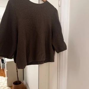 Brun stickad tröja - Säljer en mysig brun stickad tröja med trekvartsärm. Perfekt för kyliga dagar och enkel att matcha med olika outfits. Tröjan har en rund hals och en avslappnad passform.