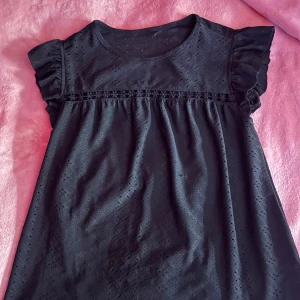 Svart blus med spetsdetaljer - svart blus med spetsdetaljer och volangärmar. Stl XS