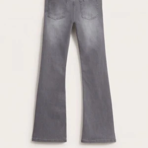 Grå bootcut jeans - Stretchiga bootcut-jeans med medelhög midja och fem fickor. Bekväma jeans med reglerbar resår på insidan av midjan för optimal passform och komfort. Dragkedjegylf, jeansknapp och skärphällor i midjan